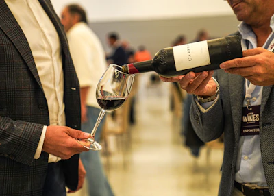A person pours red wine into a glass.