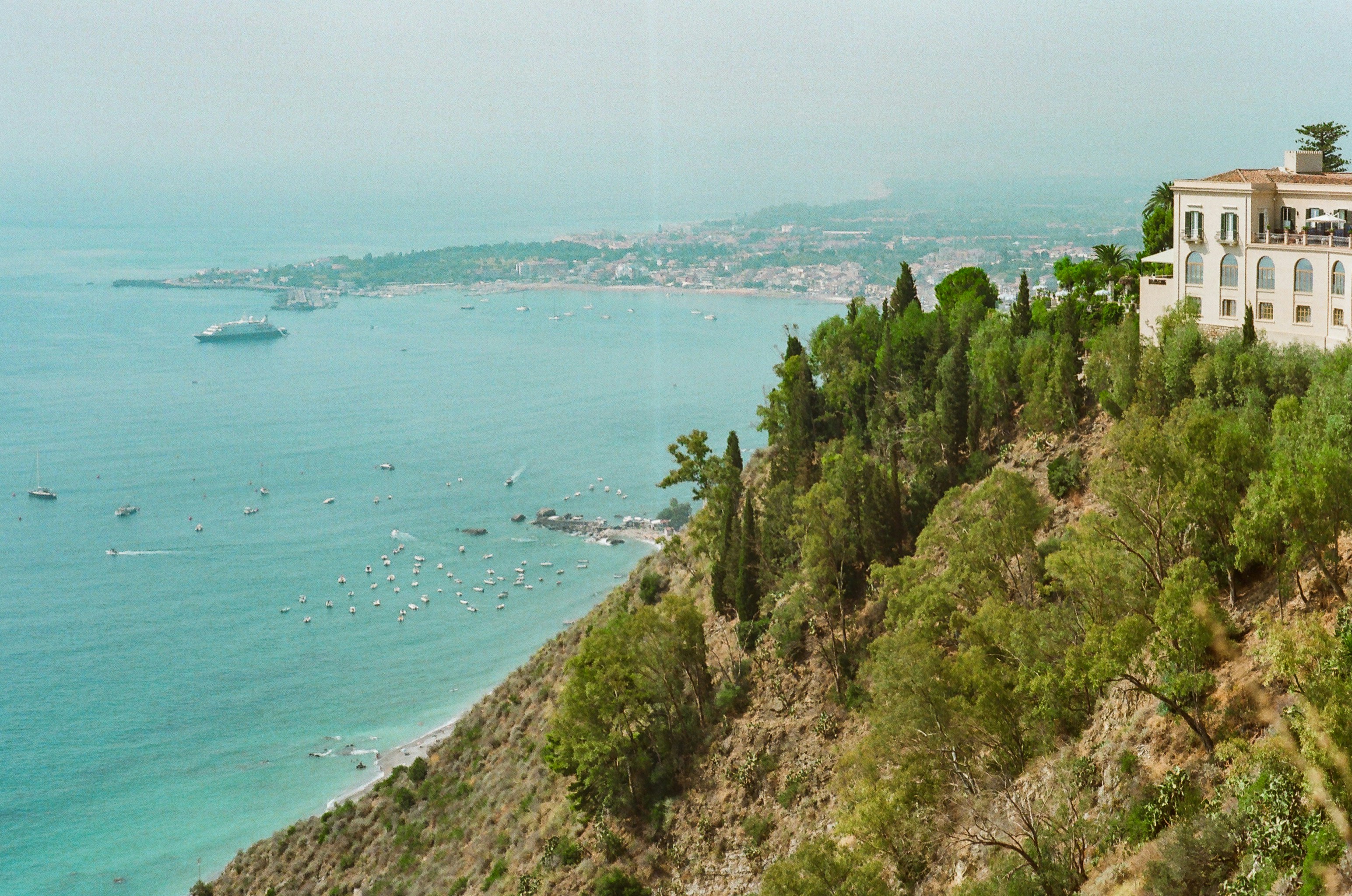 White villa on a cliff overlooking the turquoise ocean.