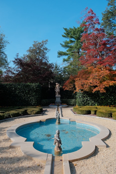 A formal garden with a fountain and statues.