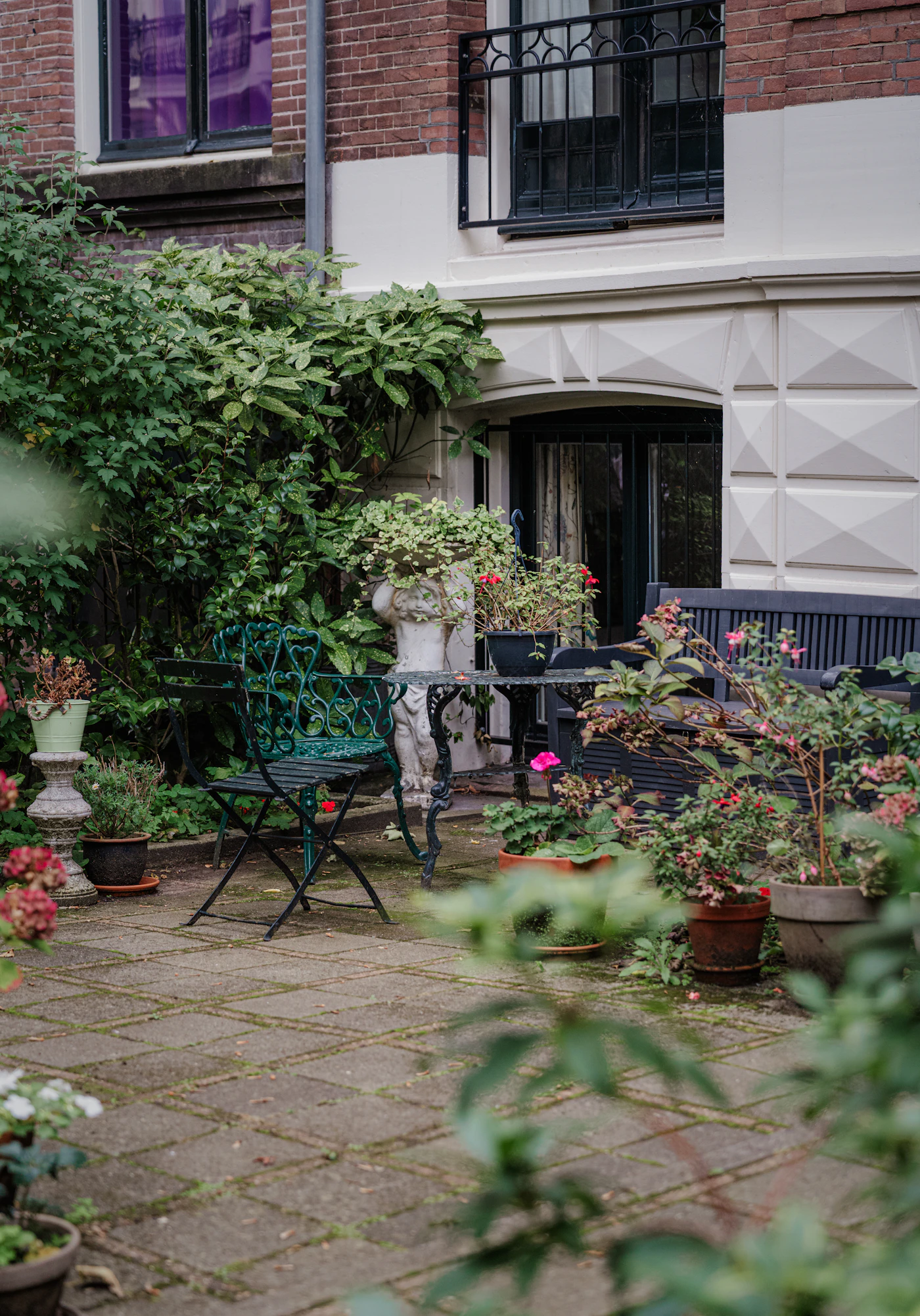 Kleiner Hofgarten mit Pflanztöpfen, Sitzplatz und dichter Bepflanzung