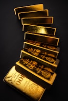 Gold bars stacked on a dark surface.