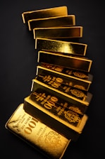 Gold bars stacked on a dark surface.