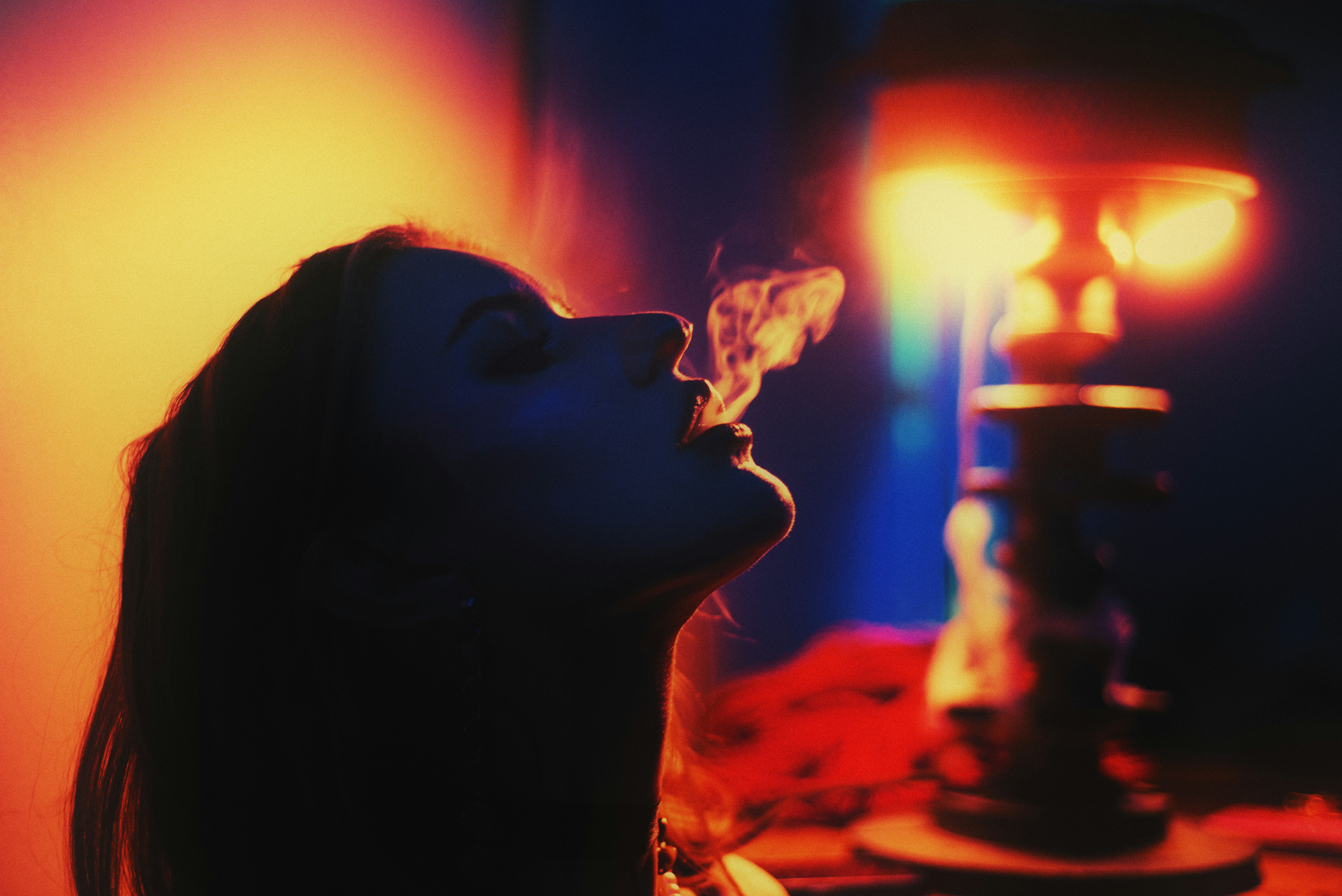 Woman exhaling smoke from a hookah pipe