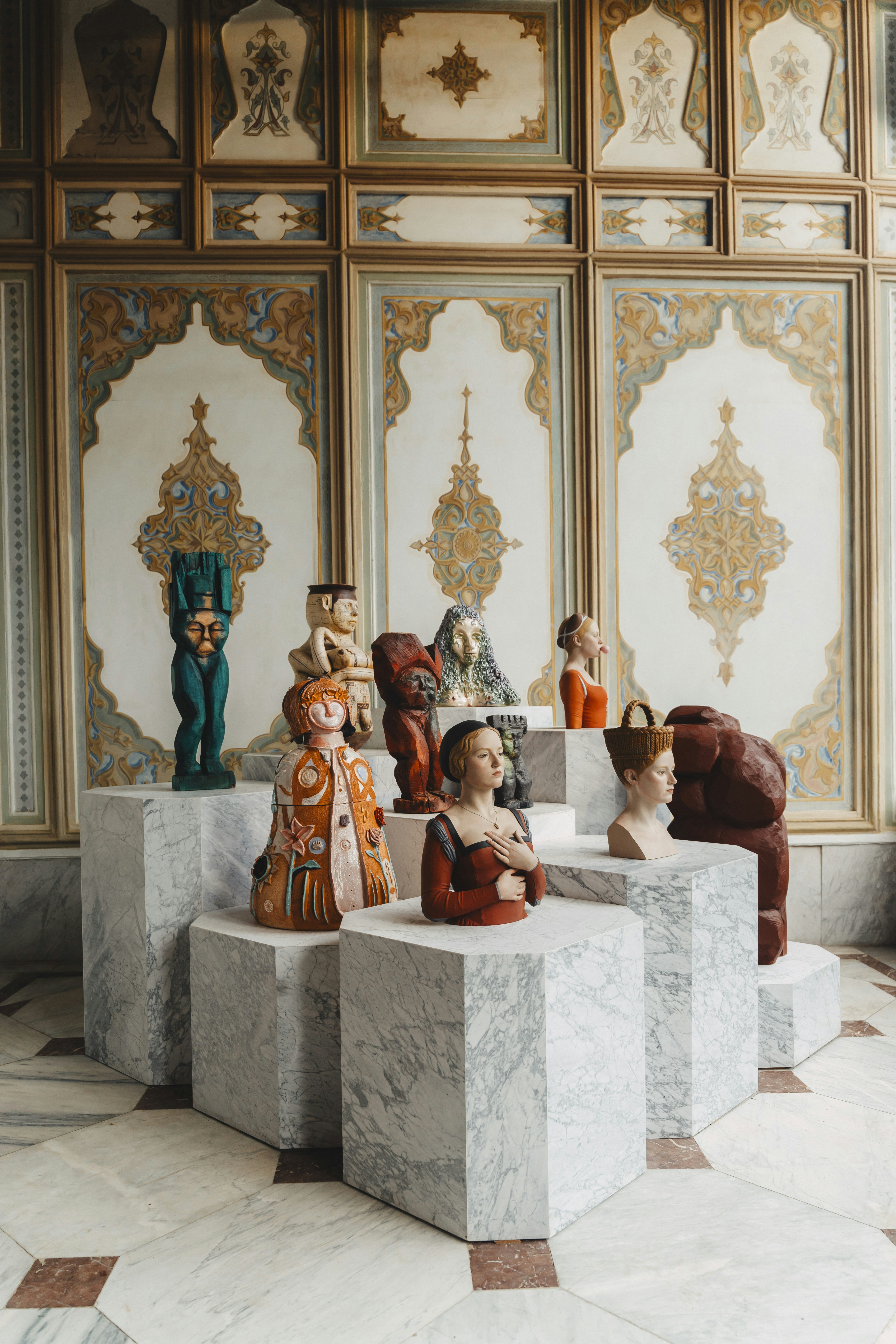 Esculturas exhibidas en pedestales de mármol en una sala ornamentada