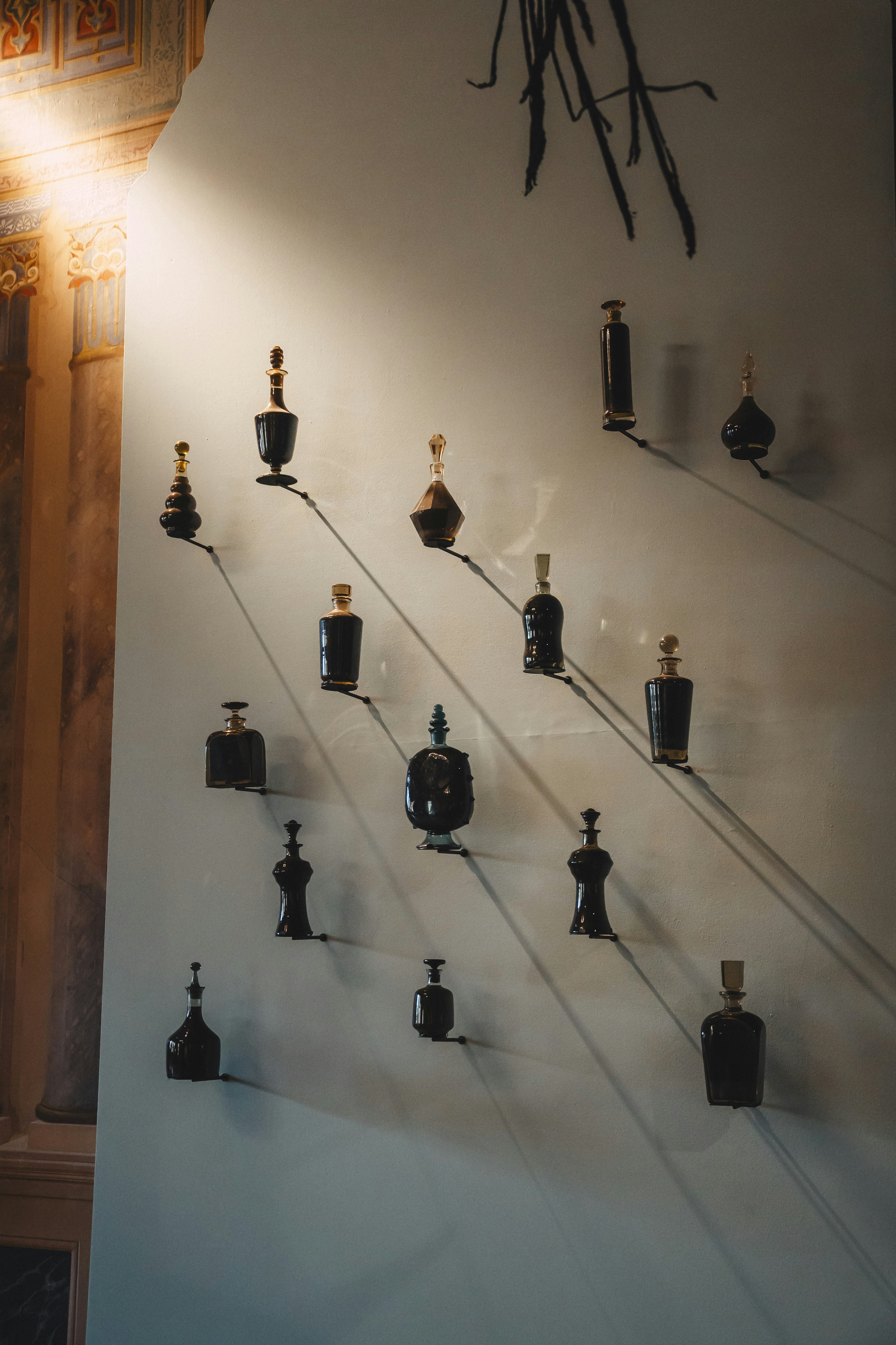 Colección de frascos de perfume antiguos expuestos en la pared.