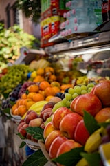 Fresh fruit stall with apples, peaches, and grapes.