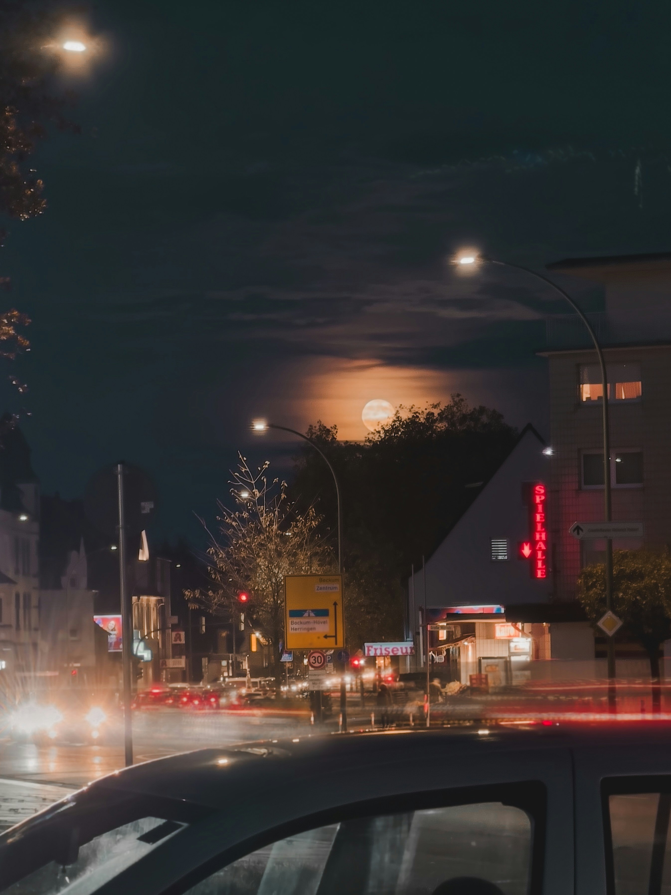 Full moon illuminates a city street at night.