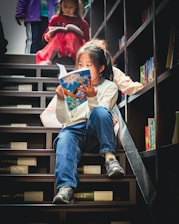 Young girl reads a book on library stairs