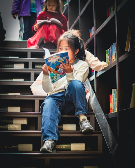 Young girl reads a book on library stairs