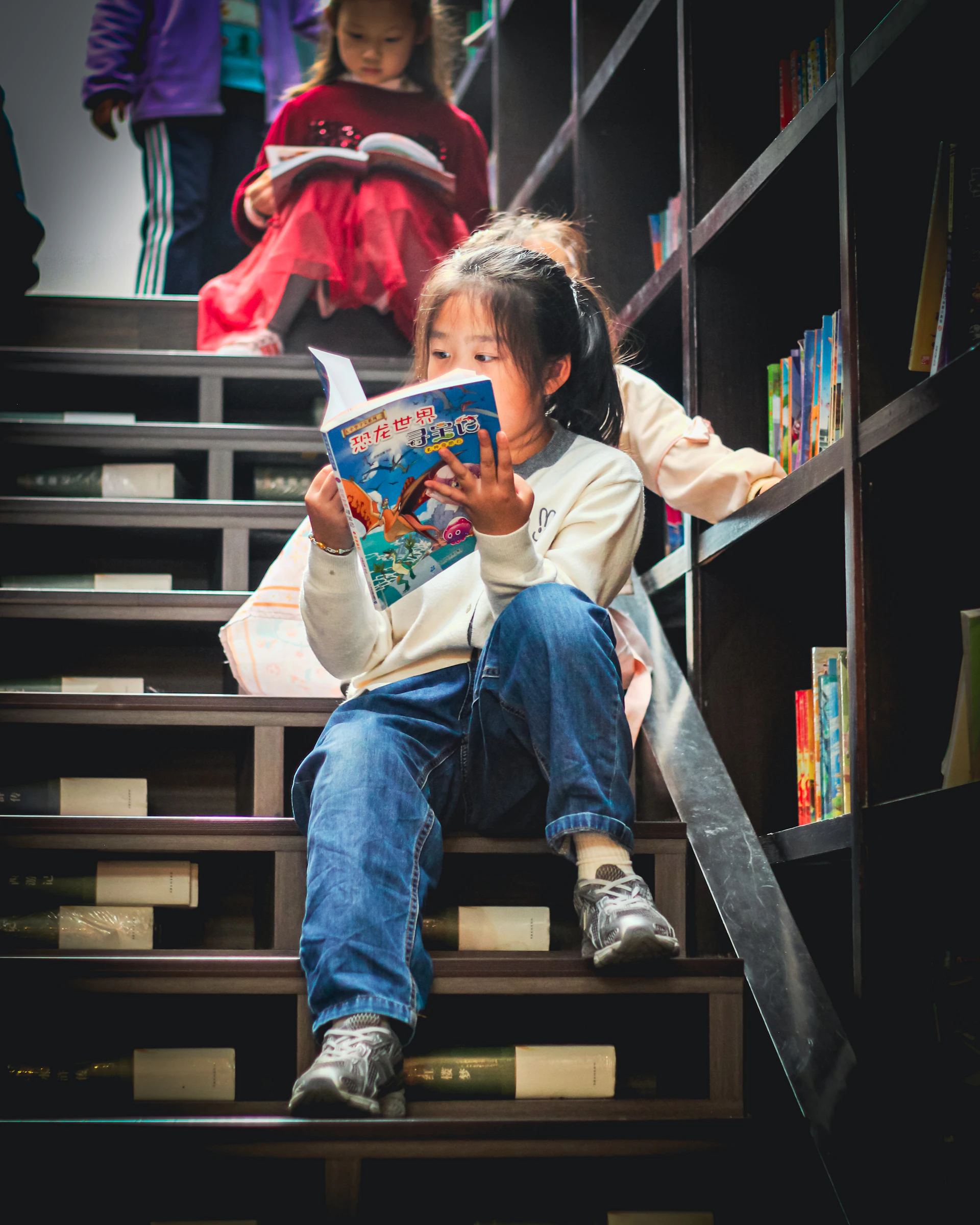 Young girl reads a book on library stairs