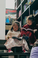 Two young girls reading books on stairs