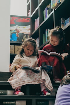 Two young girls reading books on stairs