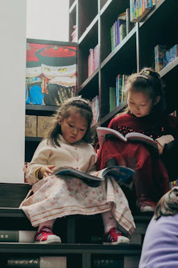 Two young girls reading books on stairs