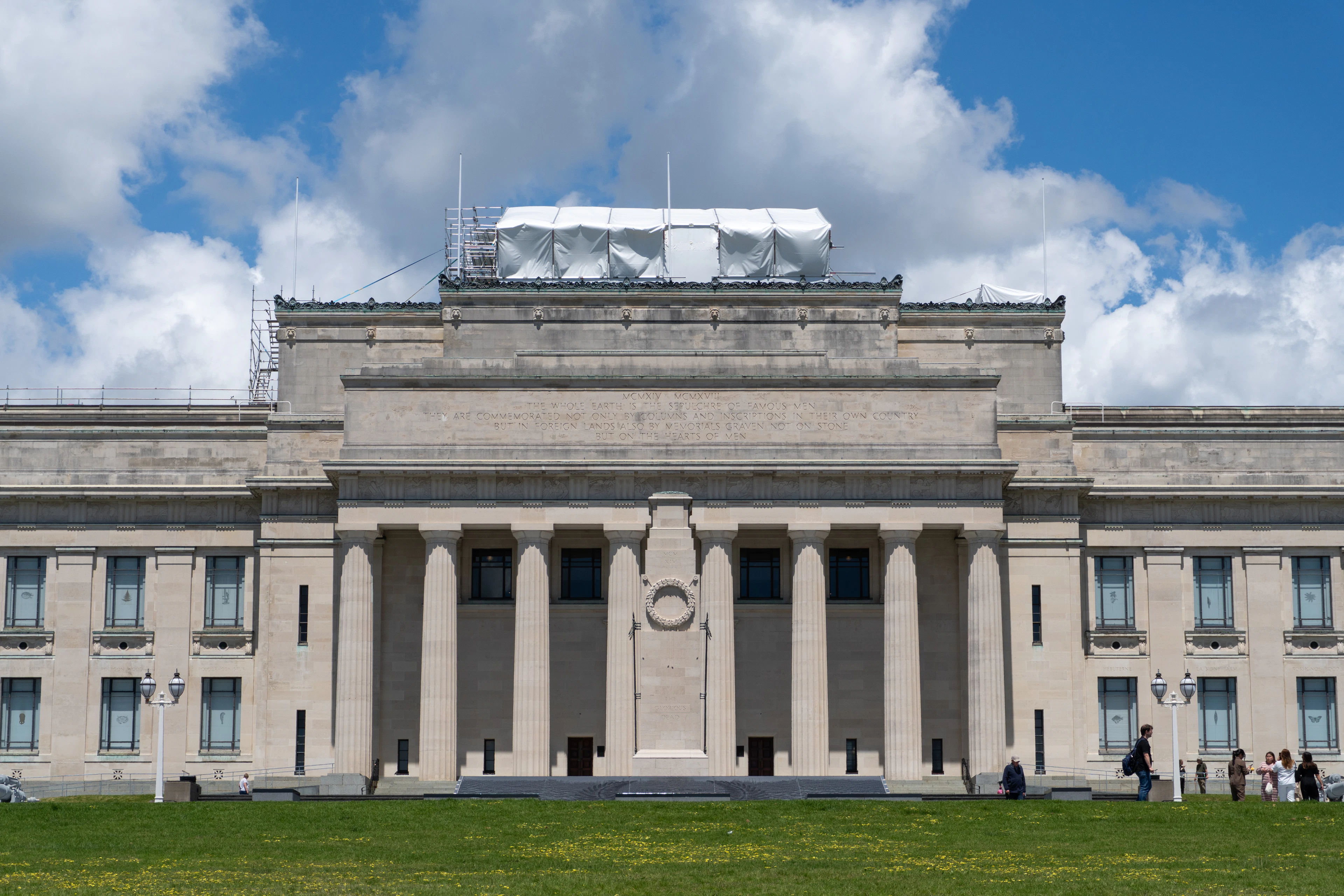 Auckland War Memorial Museum's grand columned facade under a bright blue sky with scattered clouds.