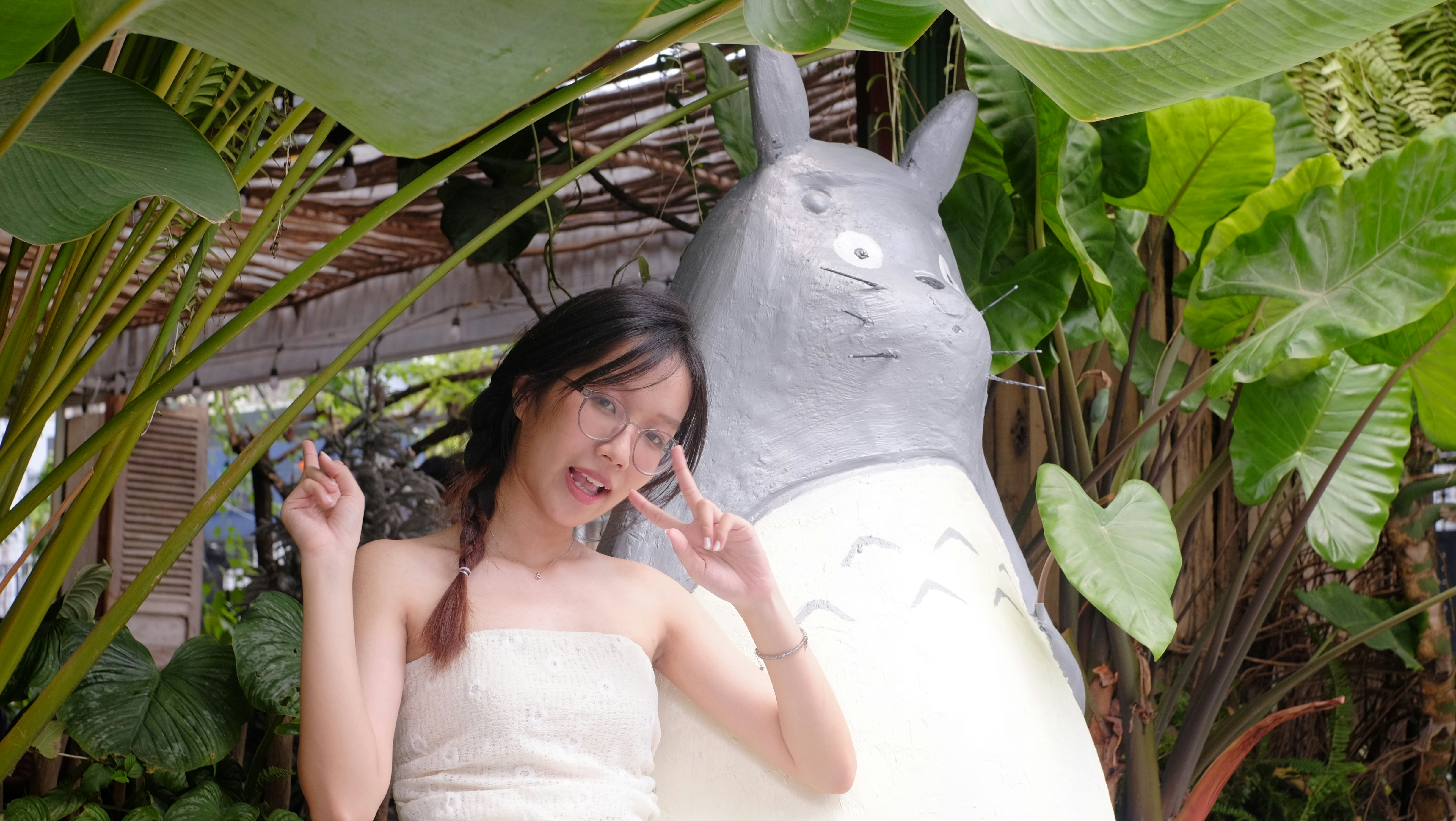 Young woman posing with totoro statue among plants