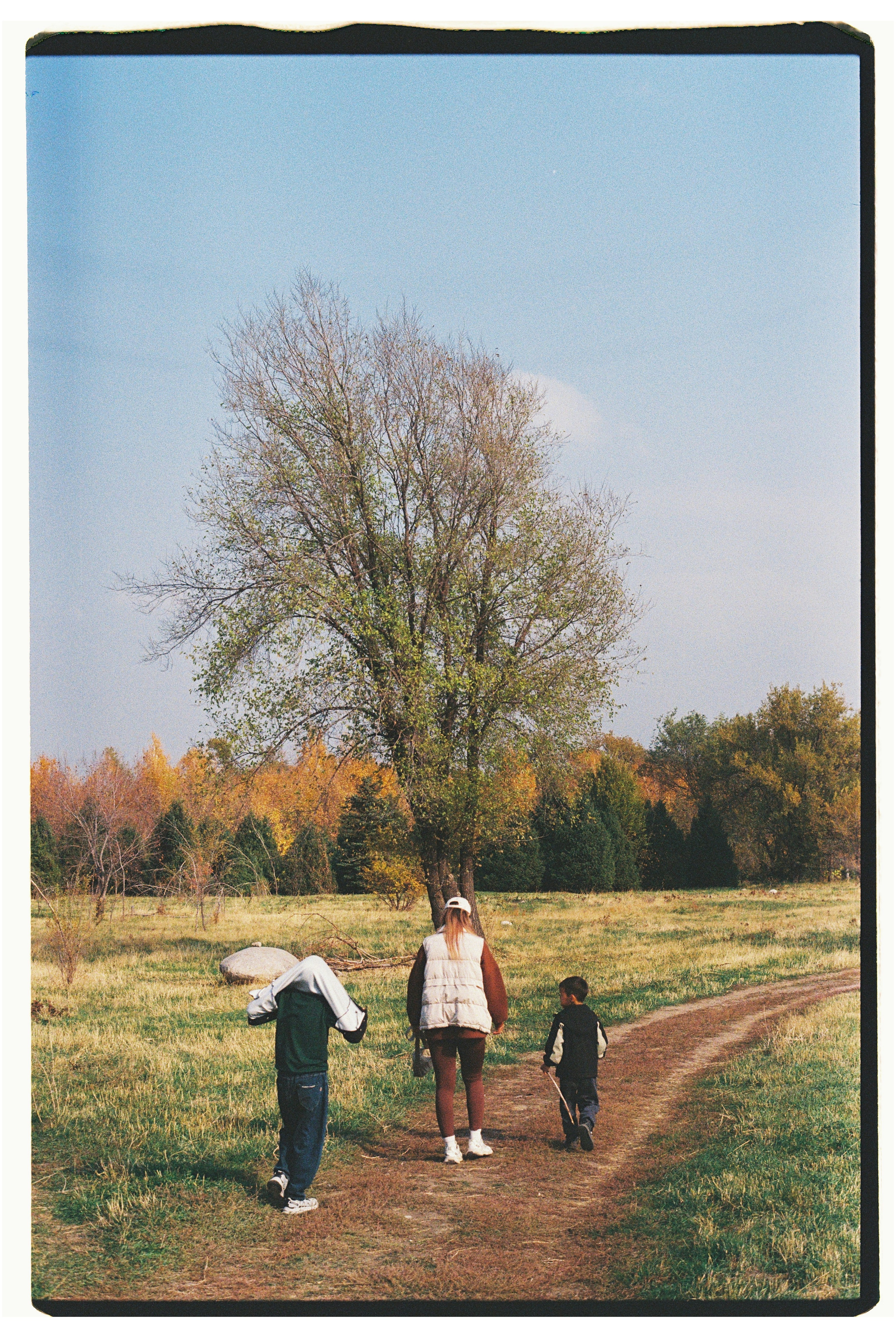 Two children and an adult walk on a path.