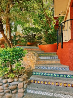 Colorful tiled stairs ascend a lush, tropical hillside.