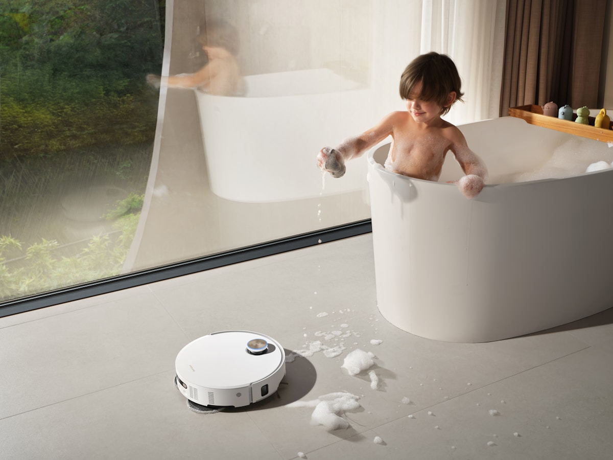 Child playing in bathtub with robot vacuum cleaner
