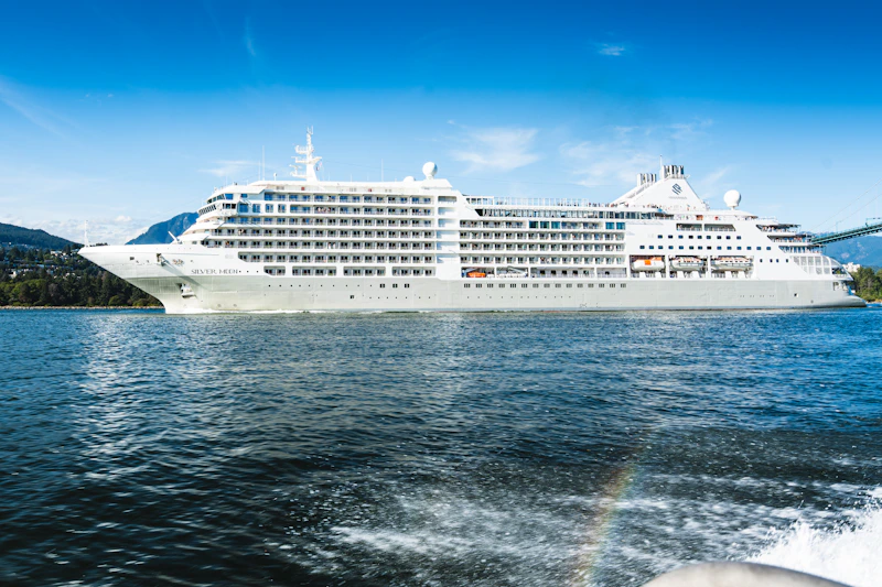 A large white cruise ship sails on a blue ocean.