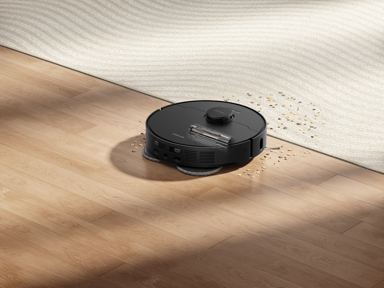 Robot vacuum cleaning spilled water and debris on floor.