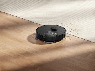 Robot vacuum cleaning spilled water and debris on floor.