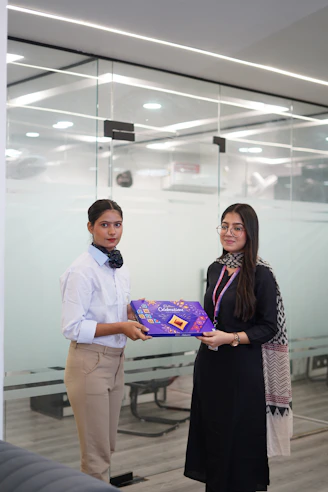 Two women holding a gift box in an office.