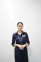 Young woman in uniform standing against white wall