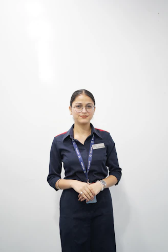 Young woman in uniform standing against white wall