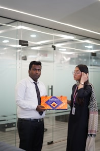Man presents gift box to woman in office
