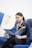 Young woman reading aviation prospectus on airplane seat.