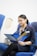 Young woman reading aviation prospectus on airplane seat.