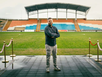Man standing on a red carpet at a stadium