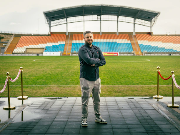 Man standing on a red carpet at a stadium