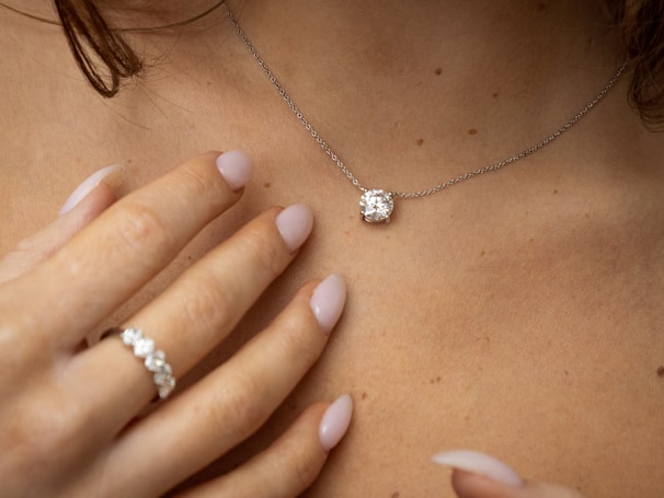Close-up of a woman's neck with diamond necklace and ring
