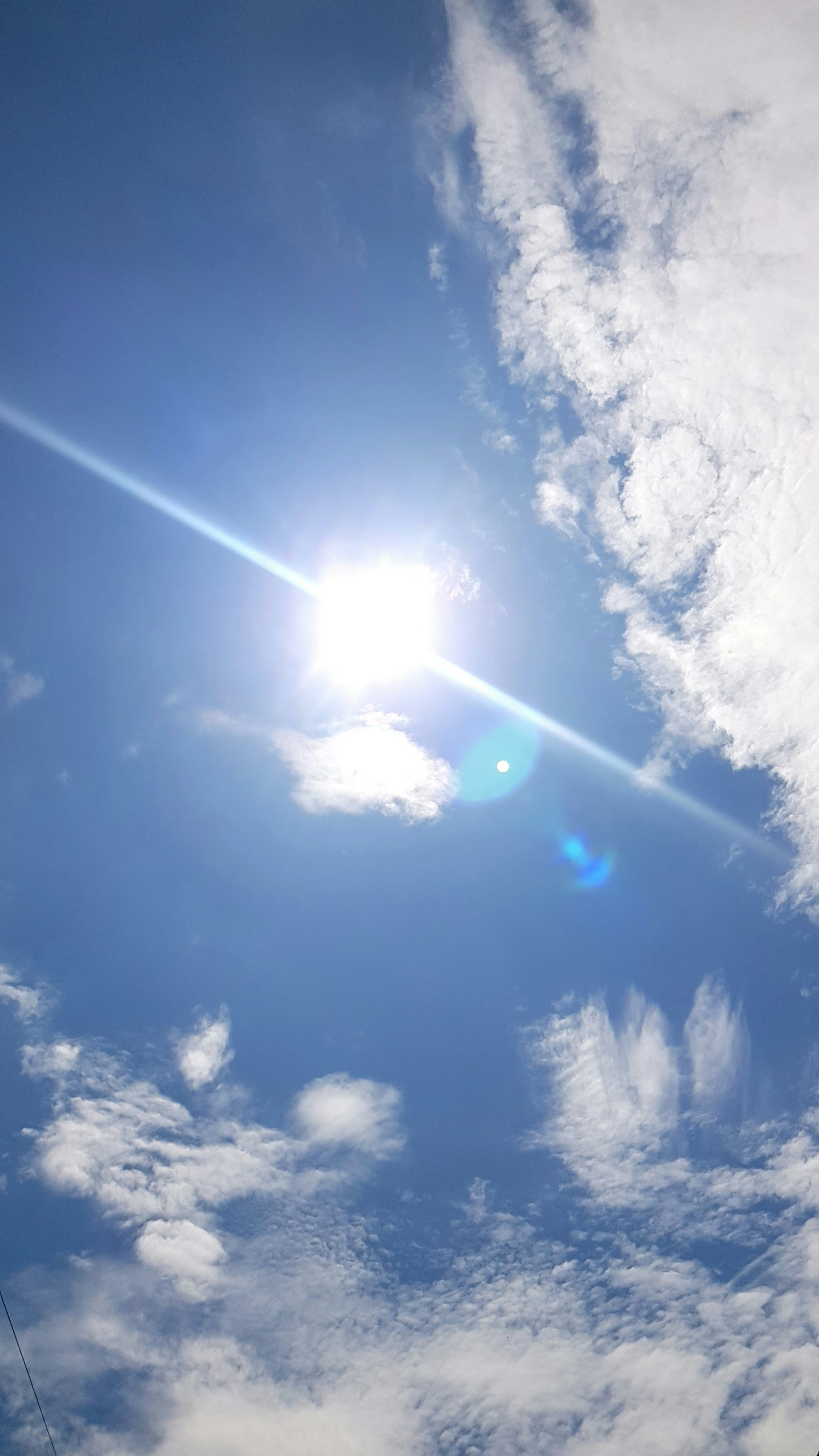 Strahlende Sonne, die durch den blauen Himmel mit Wolken scheint