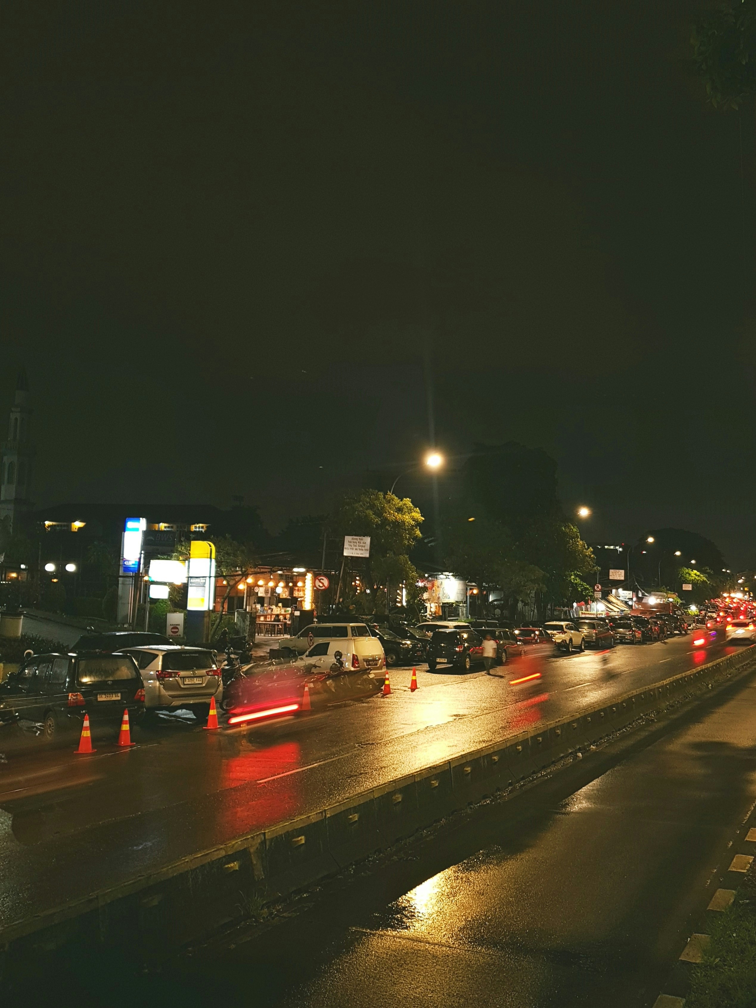 Autos auf einer nassen Straße bei Nacht mit reflektierenden Lichtern