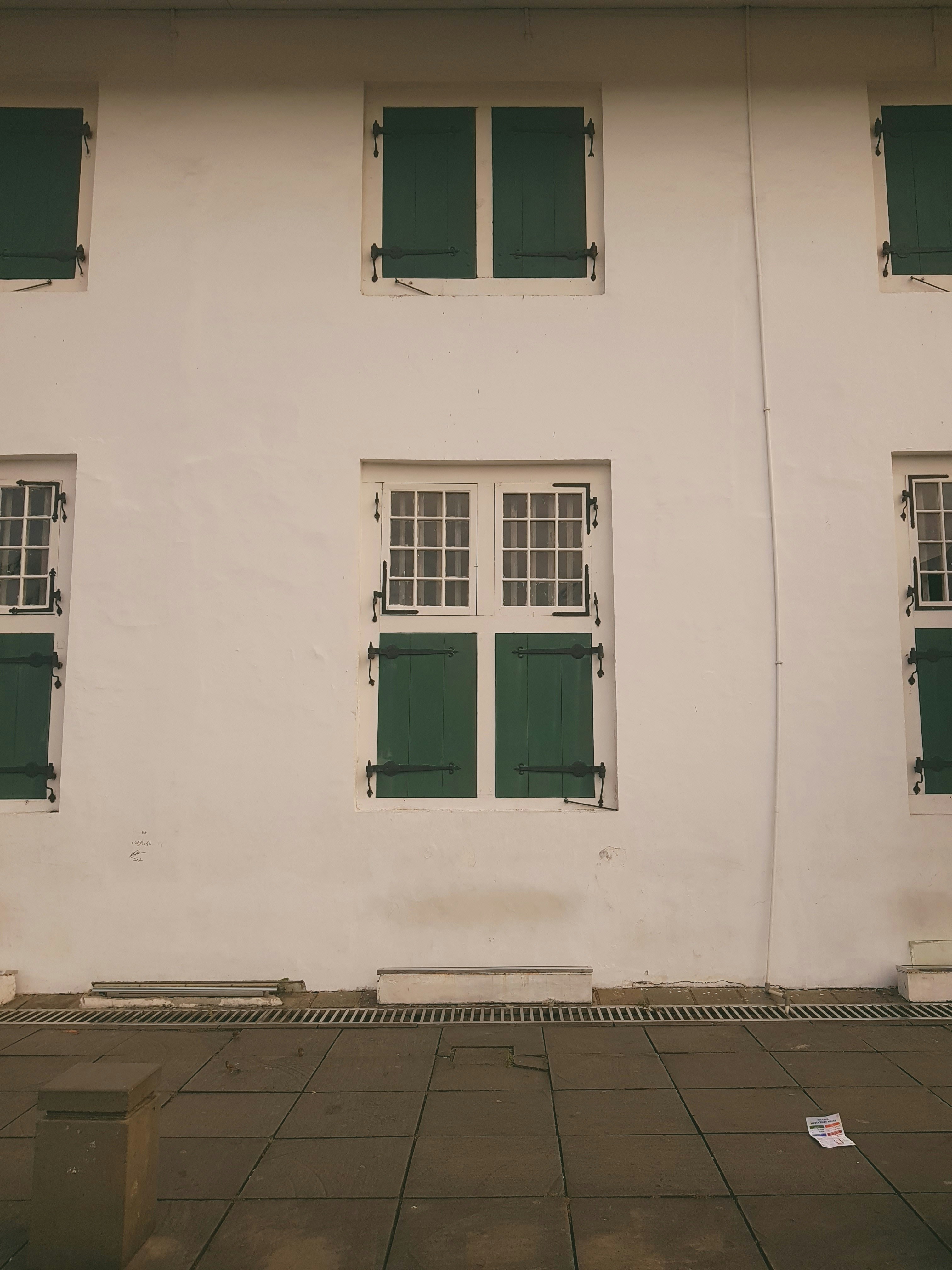 Weißes Gebäude mit grünen Fensterläden und Fenstern