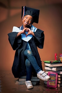 A young graduate makes a heart shape with her hands.