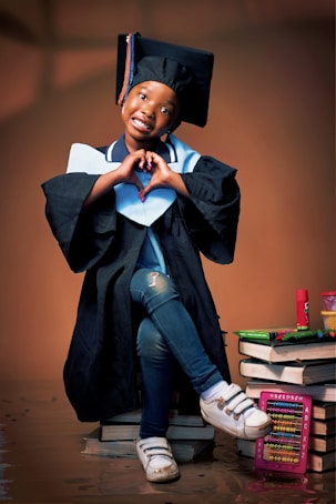 A young graduate makes a heart shape with her hands.