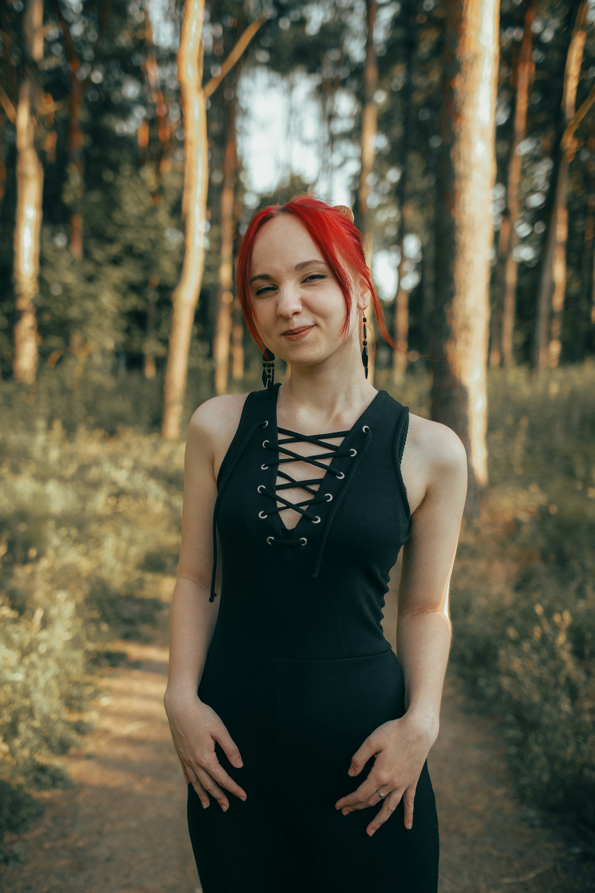 Young woman with red hair in a black dress outdoors.