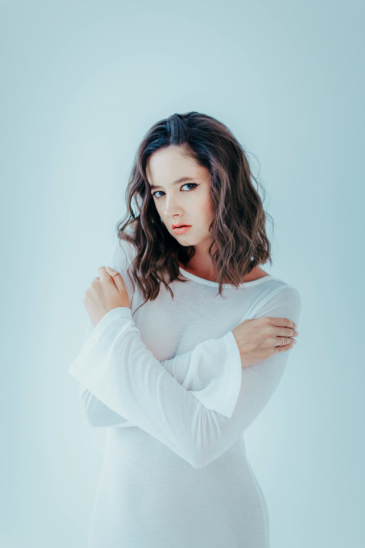 A woman in white against a pale blue wall
