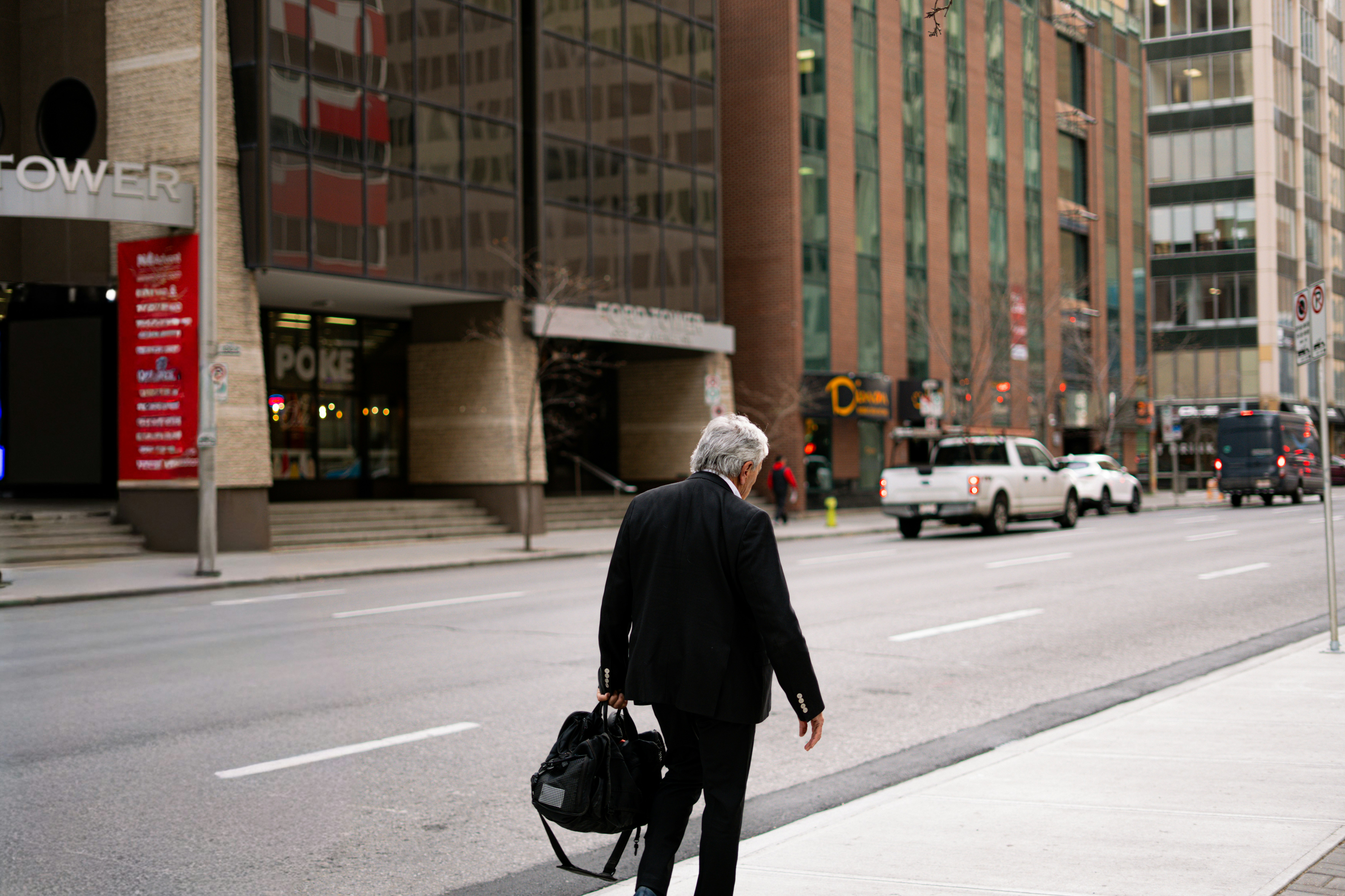 Man in suit walks down city street with briefcase.