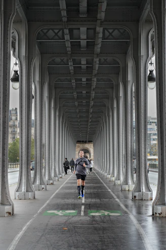 Man running on a bridge under an archway.