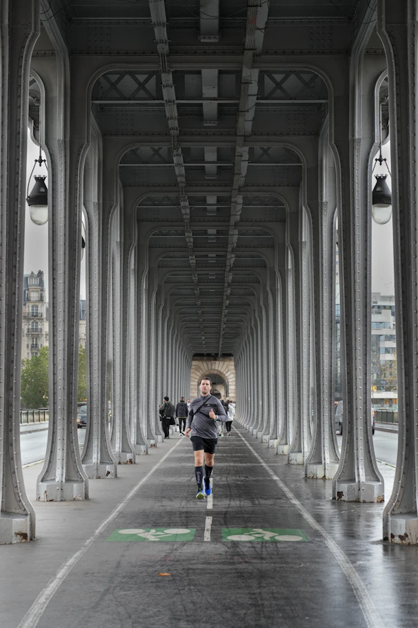 Man running on a bridge under an archway.