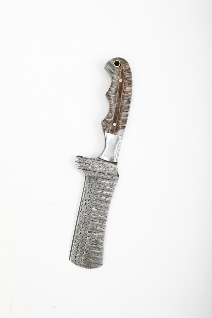 A Damascus steel knife with a wooden handle and a sharply pointed tip, in the silhouette of a honesuki boning blade