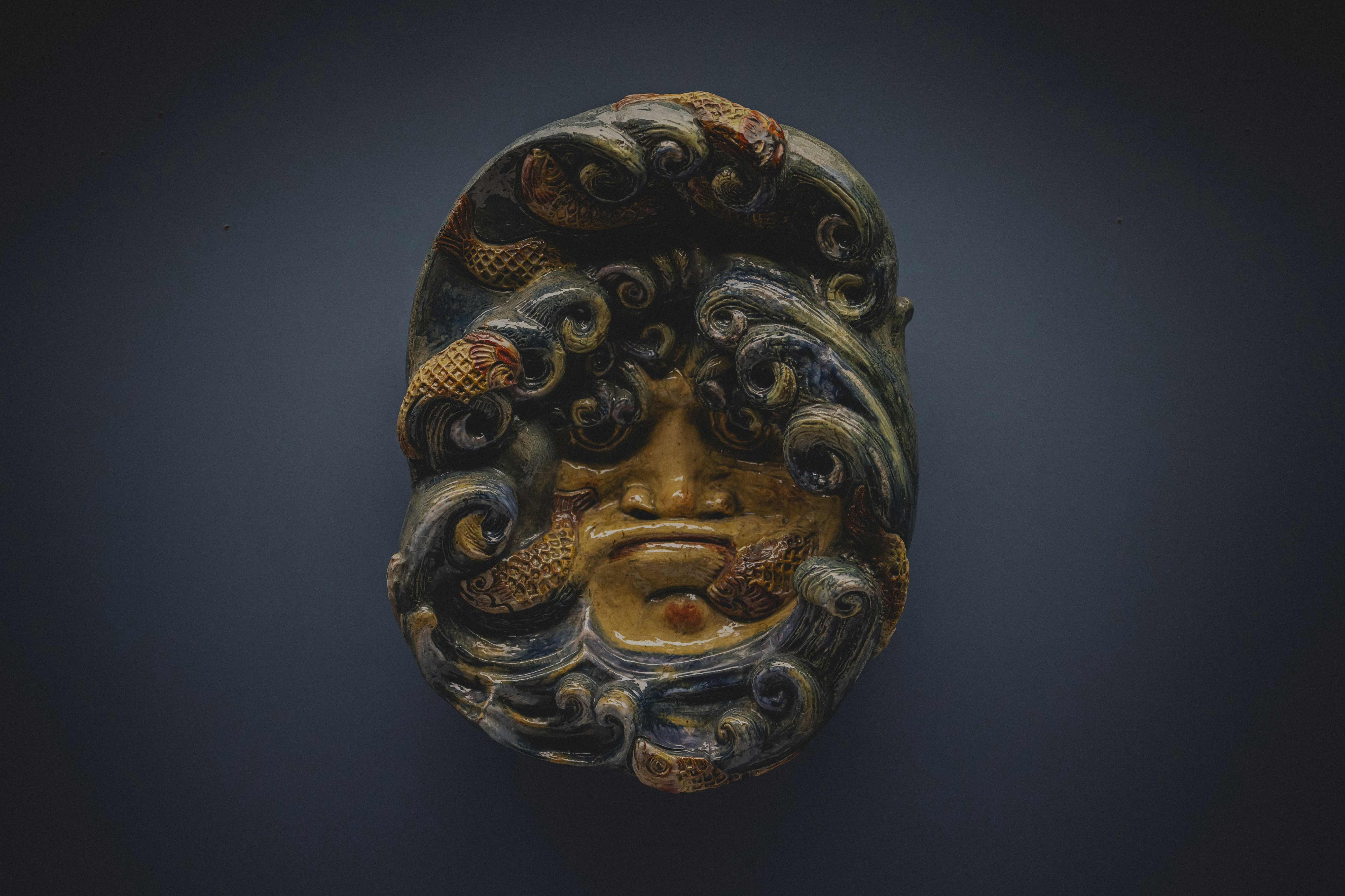 Antike Maske mit wirbelnden Mustern und gewellten Haardesigns