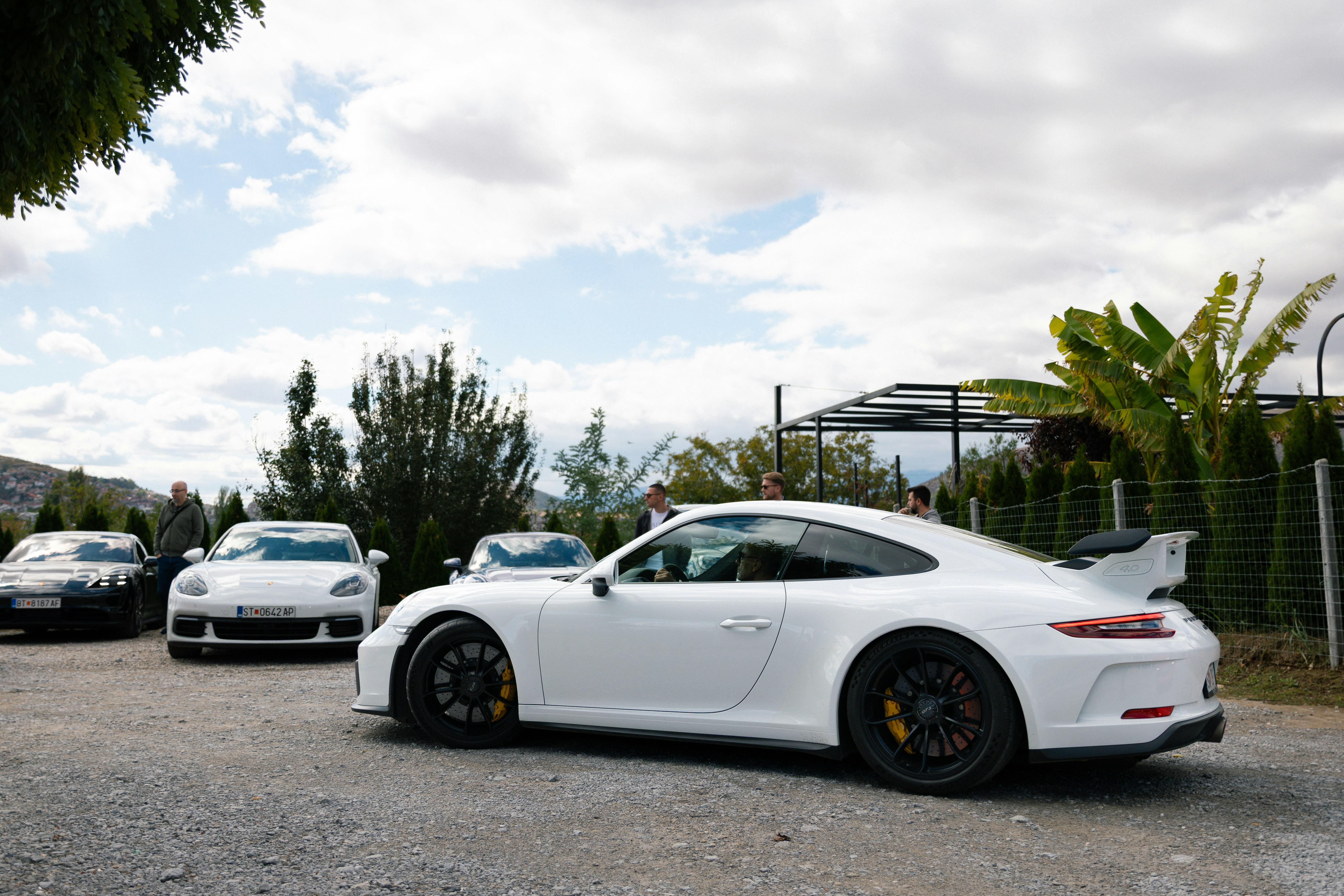 Several white porsche cars parked outdoors.