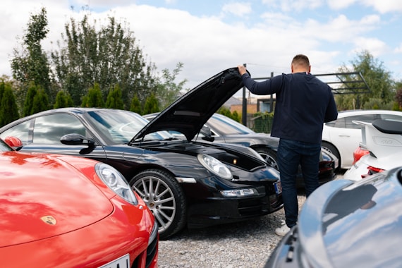 Man opens hood of black sports car