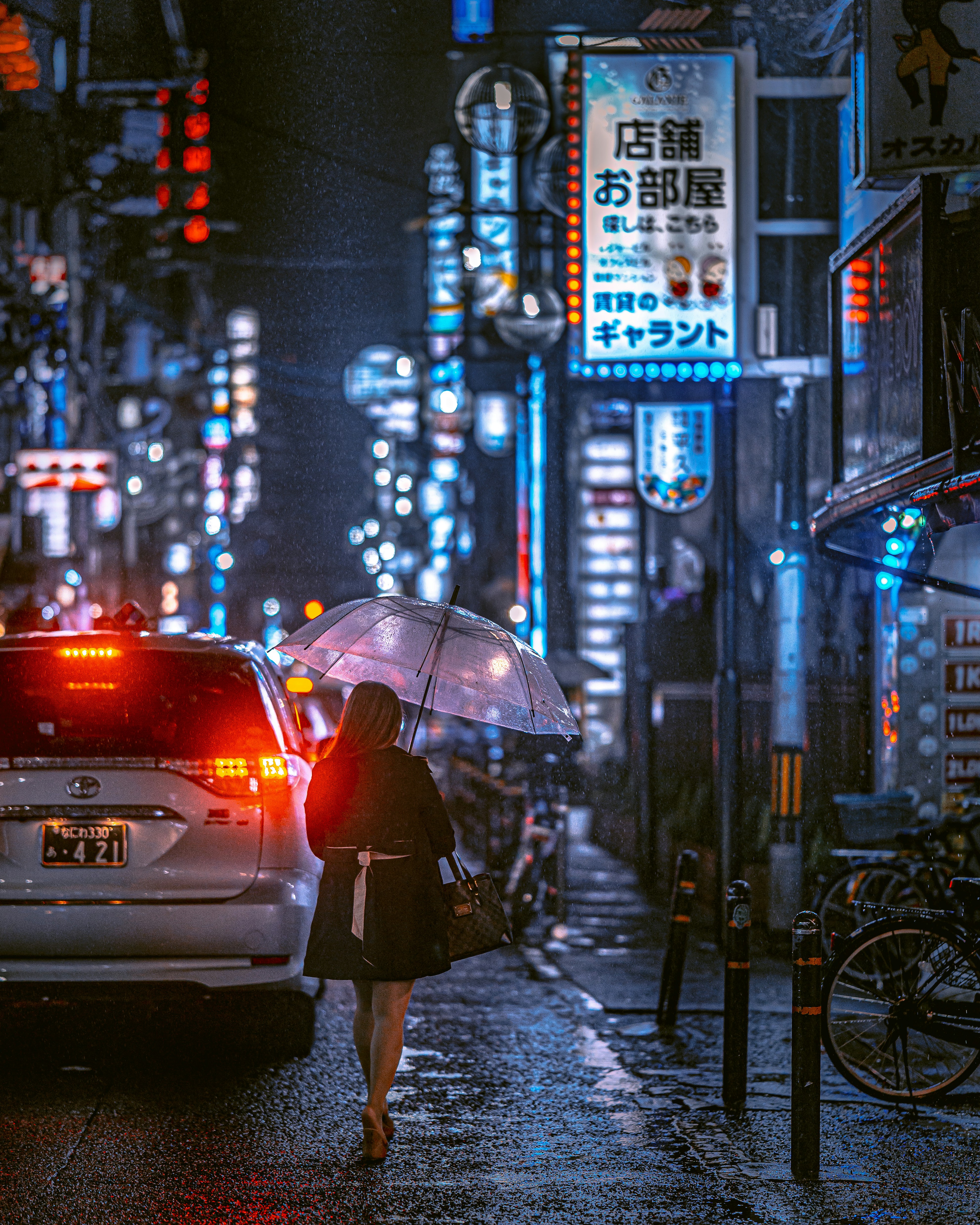 Mujer con paraguas camina por la calle lluviosa por la noche