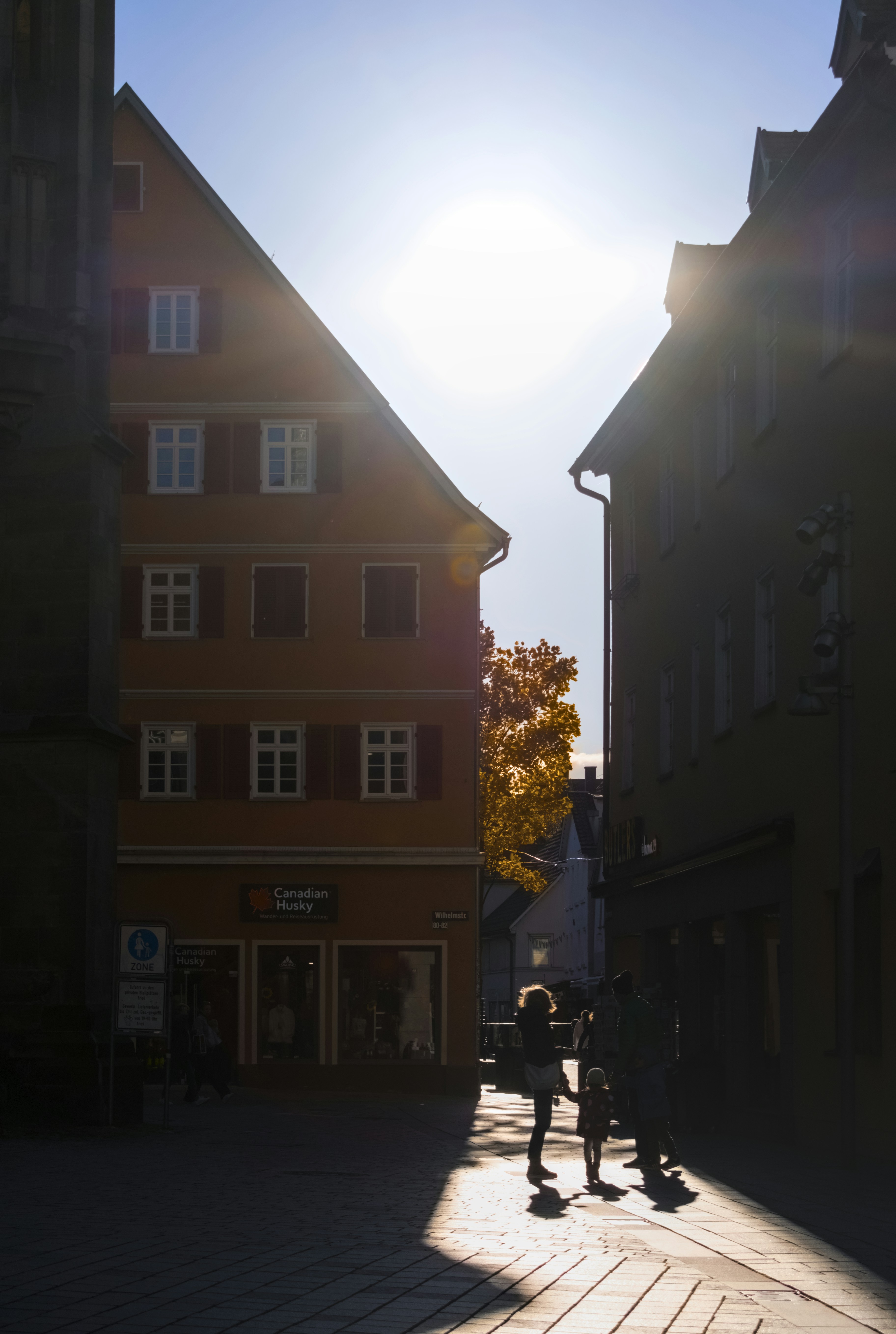 Silhouettes of people walking down a sunlit street.